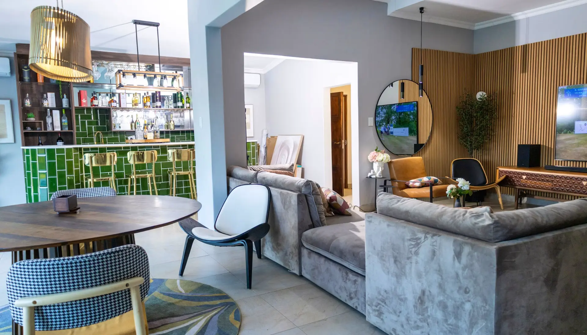 Green-tiled bar with brass stools beside the open-plan lounge