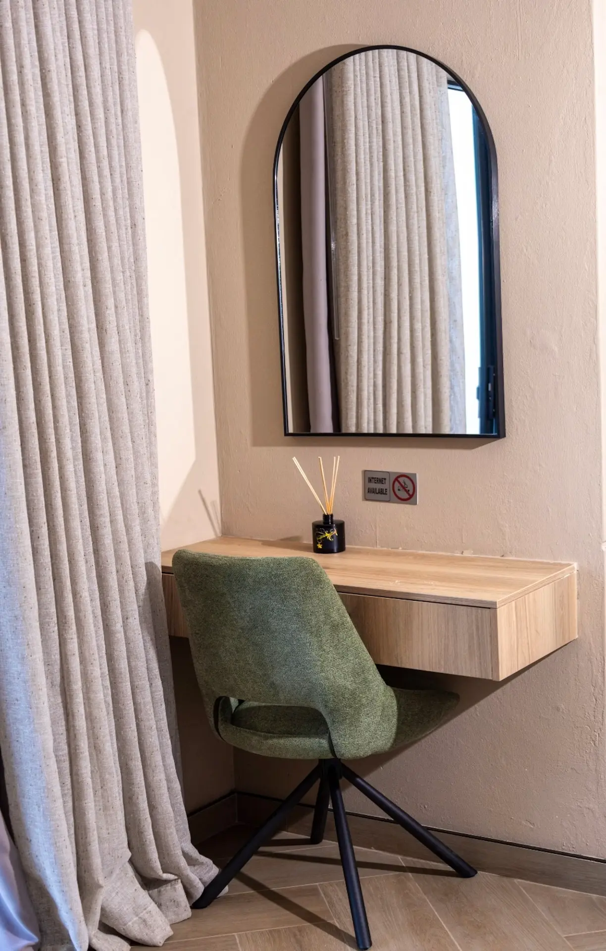 Arched mirror above a floating oak desk with a green swivel chair