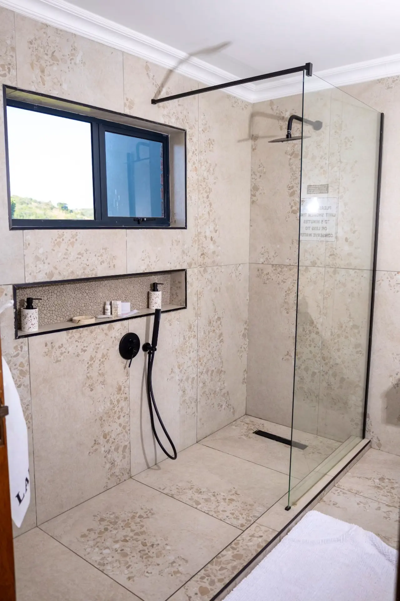 Terrazzo-tiled walk-in rain shower with matte black fittings